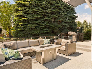 Enjoy outdoor living at its finest on this spacious deck, complete with a comfortable sectional sofa and a modern fire pit table.