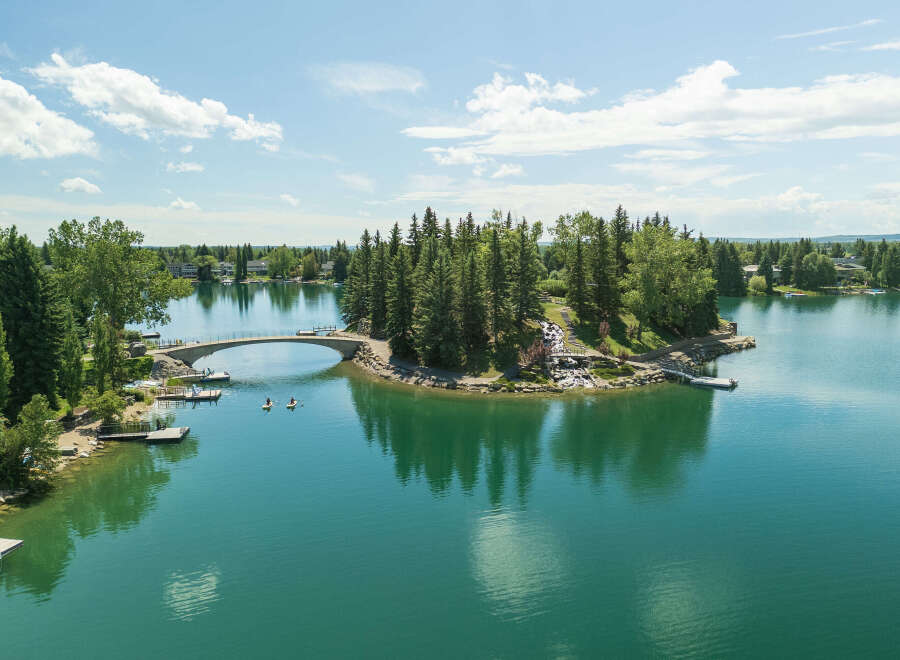 Experience lakeside living at its finest with this stunning property featuring a private island accessible by a charming arched bridge.