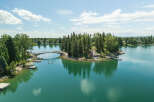 Experience lakeside living at its finest with this stunning property featuring a private island accessible by a charming arched bridge.