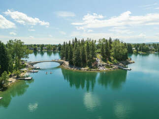 Experience lakeside living at its finest with this stunning property featuring a private island accessible by a charming arched bridge.