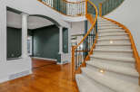 Experience grand living in this stunning home featuring a dramatic curved staircase with plush carpeting and elegant lighting.
