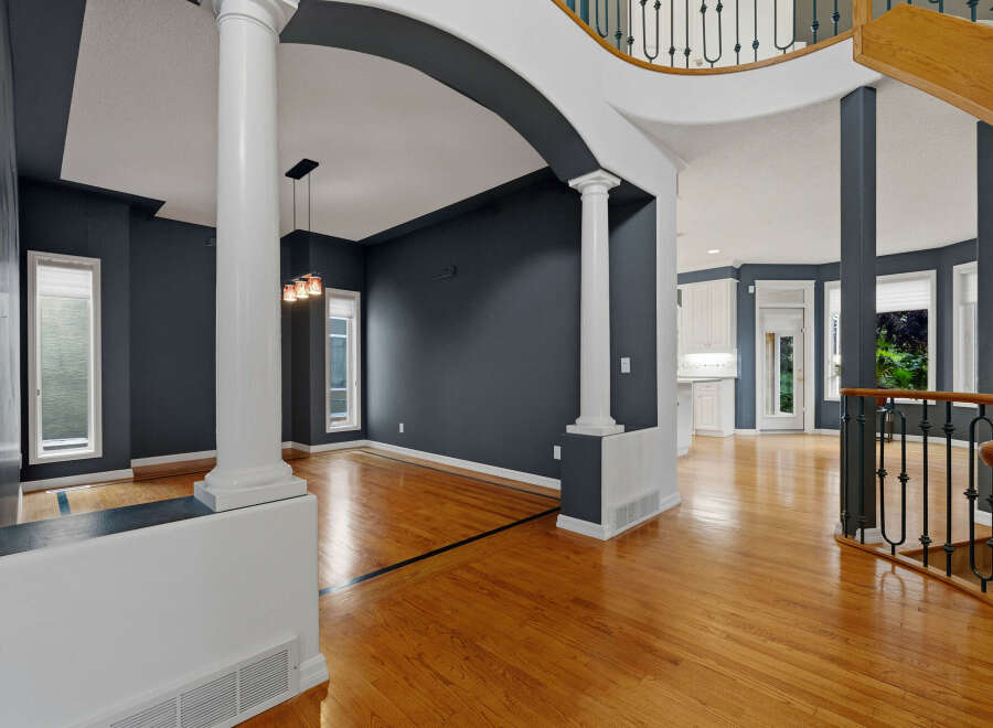 Step into this grand foyer featuring elegant white columns and a dramatic dark gray accent wall, creating a sophisticated and inviting atmosphere.