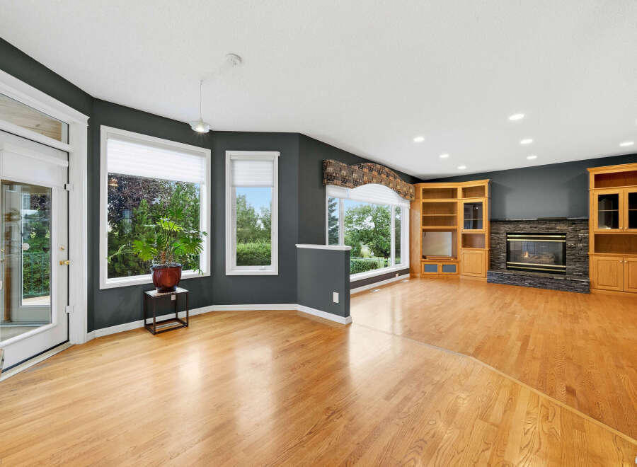 Step into this spacious living area featuring a cozy fireplace with a stone surround, complemented by elegant built-in wooden cabinetry.