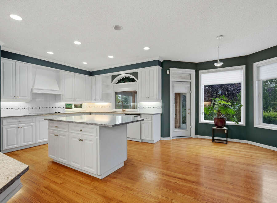 Experience the epitome of culinary delight in this stunning kitchen, featuring pristine white cabinetry and a spacious granite-topped island perfect for meal prep and entertaining.