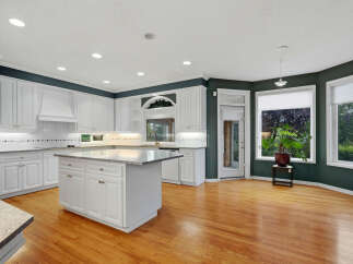 Experience the epitome of culinary delight in this stunning kitchen, featuring pristine white cabinetry and a spacious granite-topped island perfect for meal prep and entertaining.