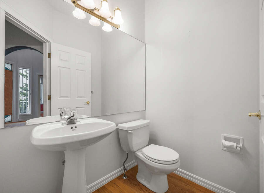 This bright and airy bathroom features a pristine white pedestal sink and a matching toilet, perfect for any modern home.