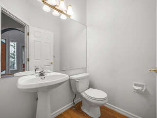This bright and airy bathroom features a pristine white pedestal sink and a matching toilet, perfect for any modern home.