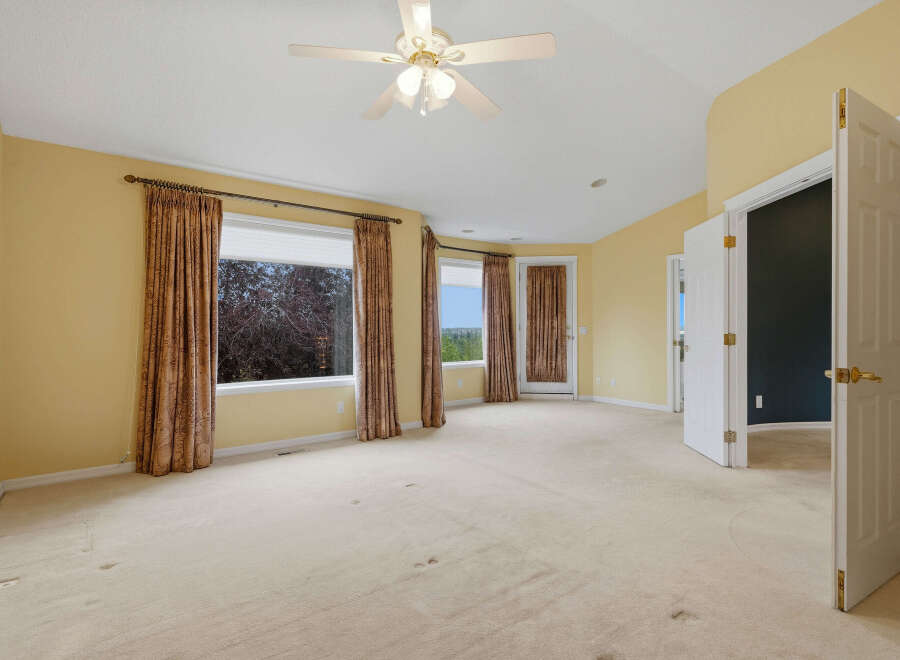 Step into this spacious bedroom featuring a ceiling fan and large windows that offer scenic views.