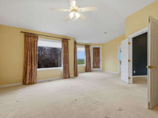 Step into this spacious bedroom featuring a ceiling fan and large windows that offer scenic views.