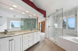 Experience luxury in this stunning master bathroom, featuring a spacious glass-enclosed marble shower and a deep soaking tub with a scenic view.
