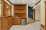 This stunning basement features a custom oak wet bar with a built-in sink, mini-fridge, and ample cabinet space, perfect for entertaining.