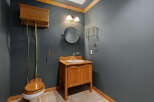 This charming bathroom features a classic high-tank toilet with a wooden seat and a matching wooden vanity with a white sink.