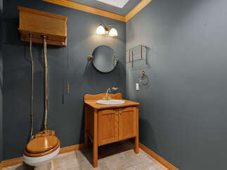 This charming bathroom features a classic high-tank toilet with a wooden seat and a matching wooden vanity with a white sink.