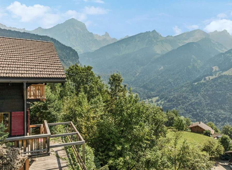 Experience breathtaking mountain views from this charming chalet, featuring a spacious wooden deck perfect for enjoying the alpine scenery.