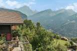 Experience breathtaking mountain views from this charming chalet, featuring a spacious wooden deck perfect for enjoying the alpine scenery.