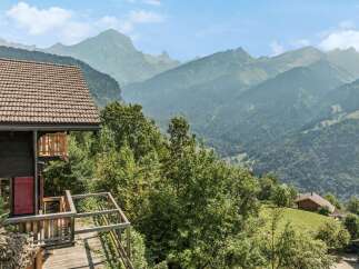 Experience breathtaking mountain views from this charming chalet, featuring a spacious wooden deck perfect for enjoying the alpine scenery.