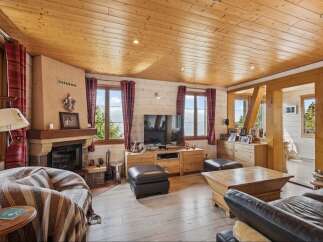 Experience cozy living in this charming mountain retreat, featuring a rustic stone fireplace and warm wooden ceilings.