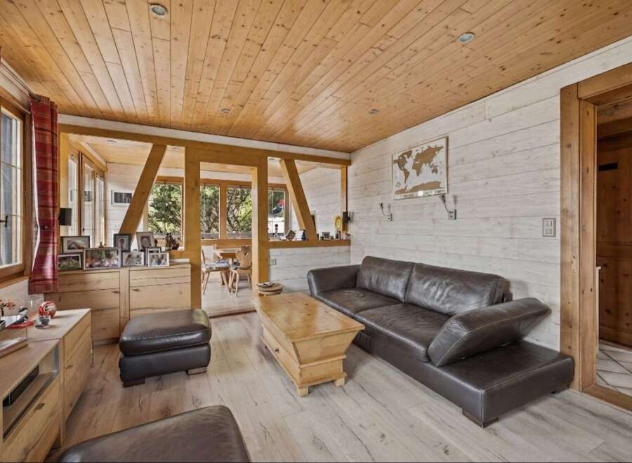 Experience rustic charm in this inviting living room, featuring a warm wooden ceiling and walls complemented by a plush leather sofa.