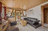 Experience rustic charm in this inviting living room, featuring a warm wooden ceiling and walls complemented by a plush leather sofa.