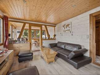 Experience rustic charm in this inviting living room, featuring a warm wooden ceiling and walls complemented by a plush leather sofa.