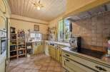 Discover this charming kitchen featuring light yellow cabinetry with contrasting green trim, complemented by a warm, tiled backsplash and a rustic wooden ceiling.