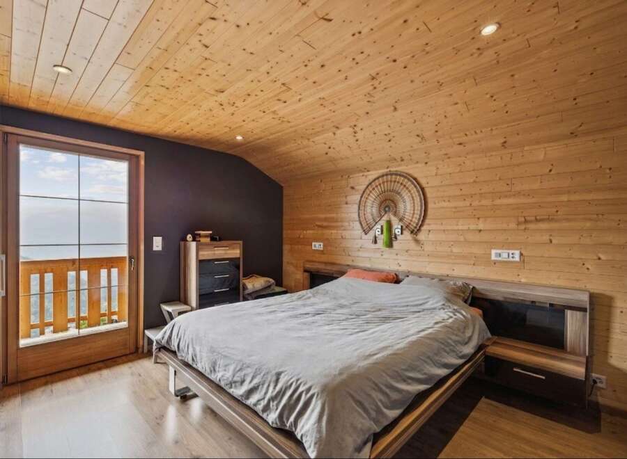 Experience rustic charm in this cozy bedroom featuring a wooden-paneled ceiling and walls, creating a warm and inviting atmosphere.