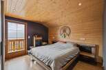 Experience rustic charm in this cozy bedroom featuring a wooden-paneled ceiling and walls, creating a warm and inviting atmosphere.