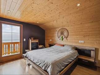 Experience rustic charm in this cozy bedroom featuring a wooden-paneled ceiling and walls, creating a warm and inviting atmosphere.