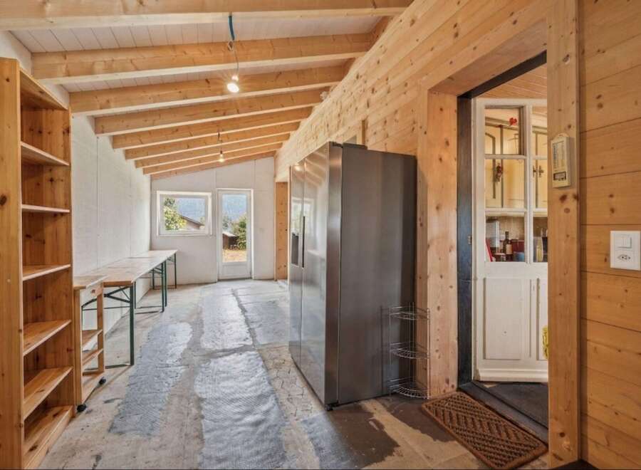 Discover this spacious room with a rustic wooden ceiling and walls, perfect for a workshop or storage area.