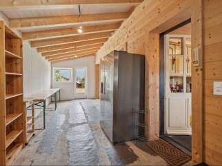 Discover this spacious room with a rustic wooden ceiling and walls, perfect for a workshop or storage area.