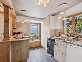 Experience rustic charm in this cozy kitchen featuring natural wood cabinetry and a stunning view of the mountains through the glass door.