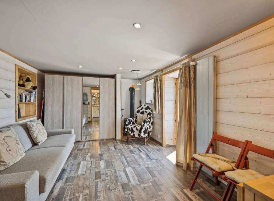 Experience cozy living in this charming cabin-style room, featuring a comfortable sofa and a unique cow-print armchair perfect for relaxation.