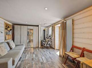 Experience cozy living in this charming cabin-style room, featuring a comfortable sofa and a unique cow-print armchair perfect for relaxation.
