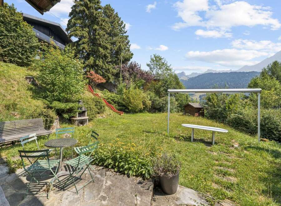 Enjoy outdoor living in this charming backyard featuring a red slide for endless fun and a picnic table with chairs for al fresco dining.