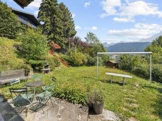 Enjoy outdoor living in this charming backyard featuring a red slide for endless fun and a picnic table with chairs for al fresco dining.