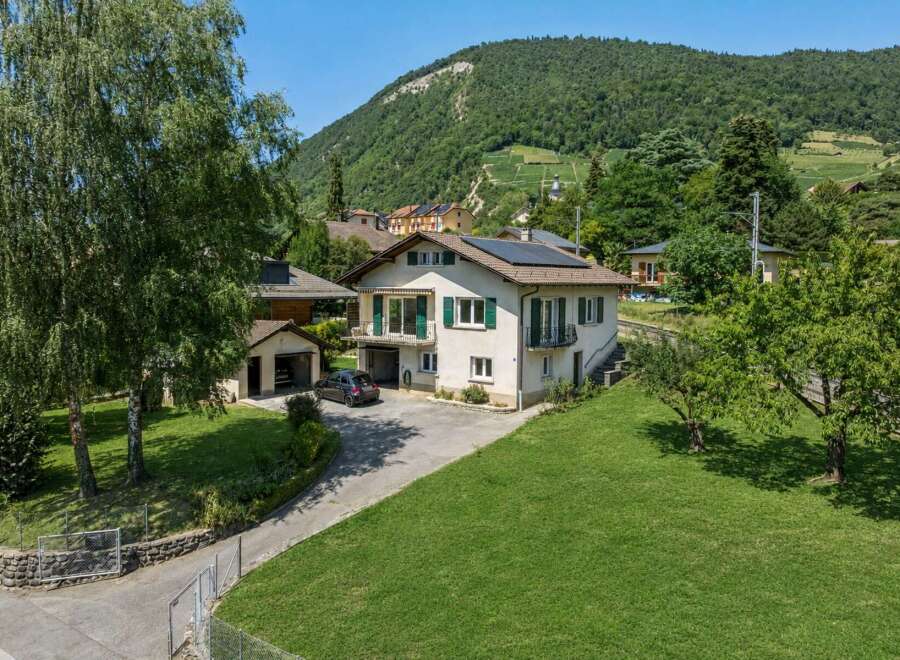 Discover this charming property nestled against a lush green hillside, offering breathtaking views of the surrounding landscape.