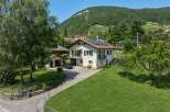 Discover this charming property nestled against a lush green hillside, offering breathtaking views of the surrounding landscape.