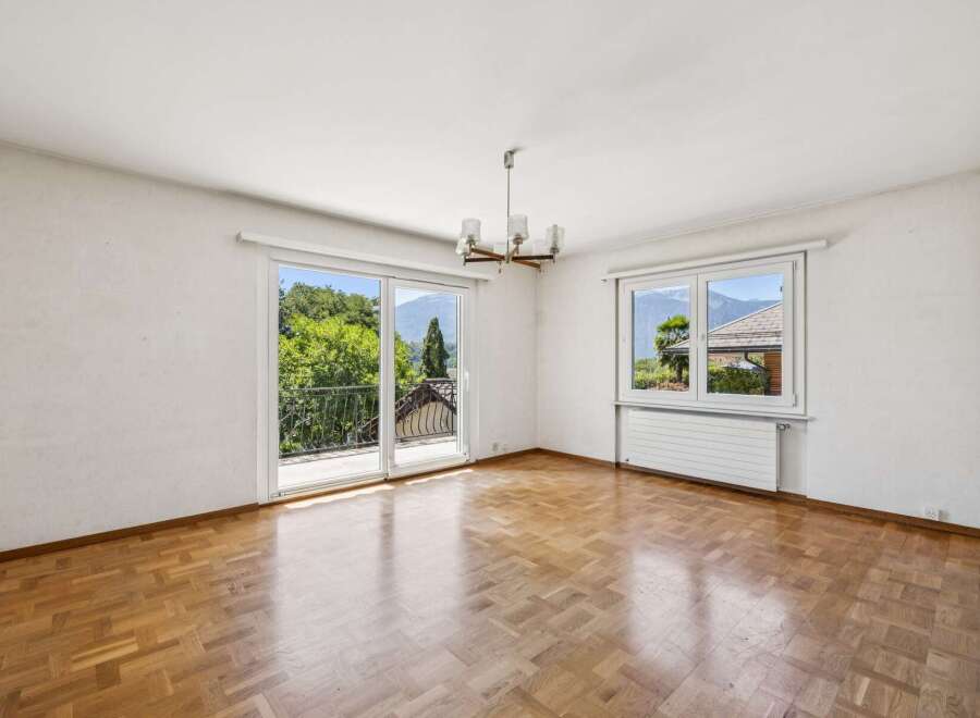 Experience breathtaking mountain views from this spacious living area, featuring a large sliding glass door that opens to a balcony.