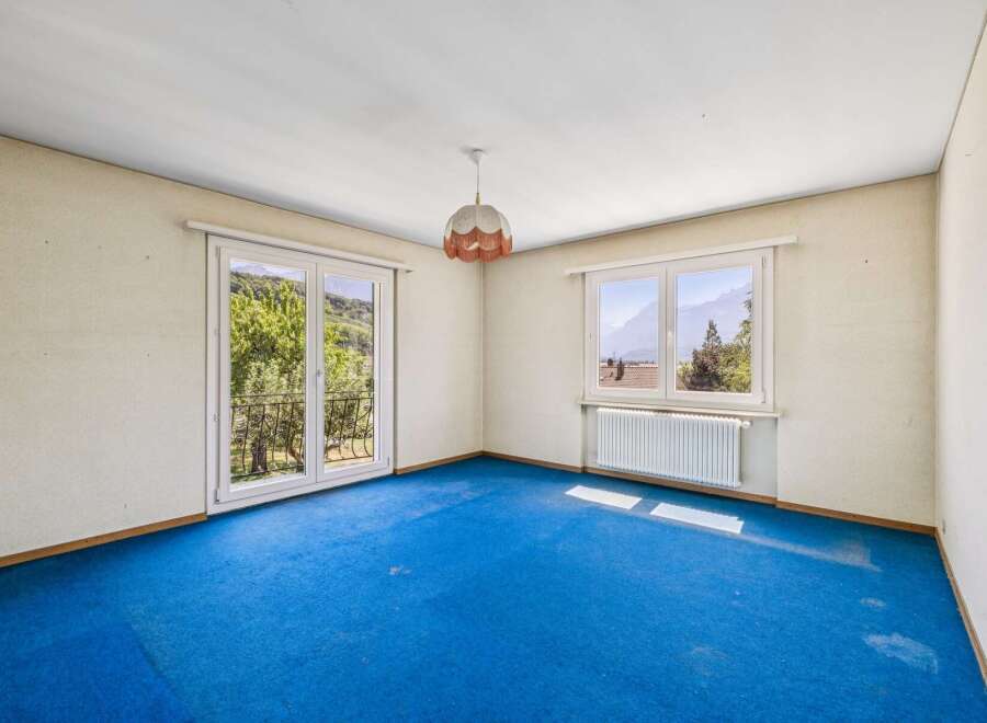 Experience breathtaking mountain views from this spacious room featuring a large double door leading to a balcony and an additional window.