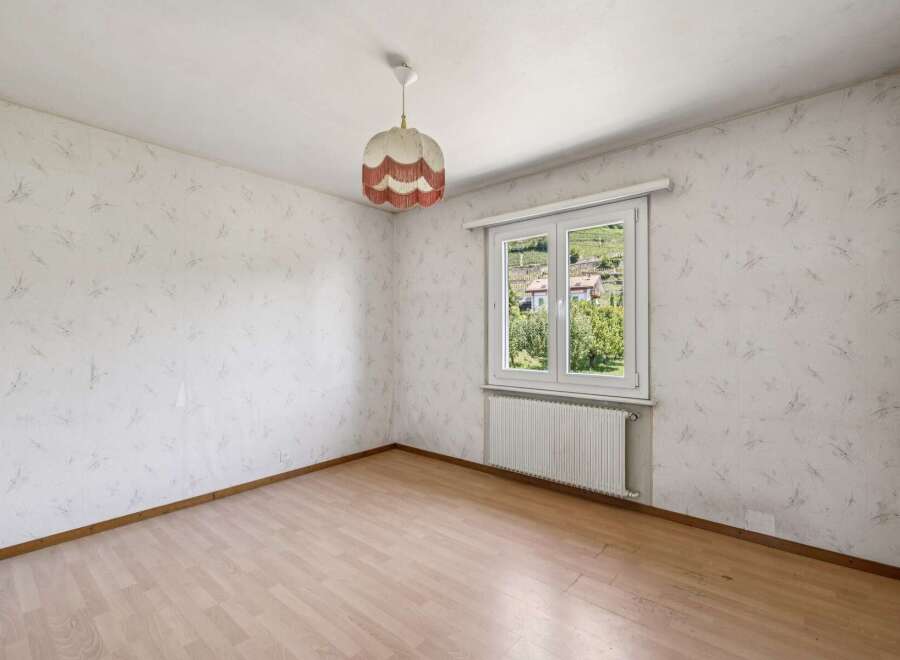 This charming room features light wood laminate flooring and walls adorned with a delicate, abstract wallpaper pattern.
