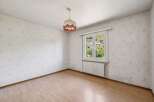 This charming room features light wood laminate flooring and walls adorned with a delicate, abstract wallpaper pattern.