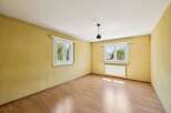 This empty room features a warm yellow textured wall and a light wood laminate floor, creating a cozy atmosphere.