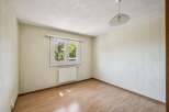 This empty room features a large window with a view of lush green trees, flooding the space with natural light.