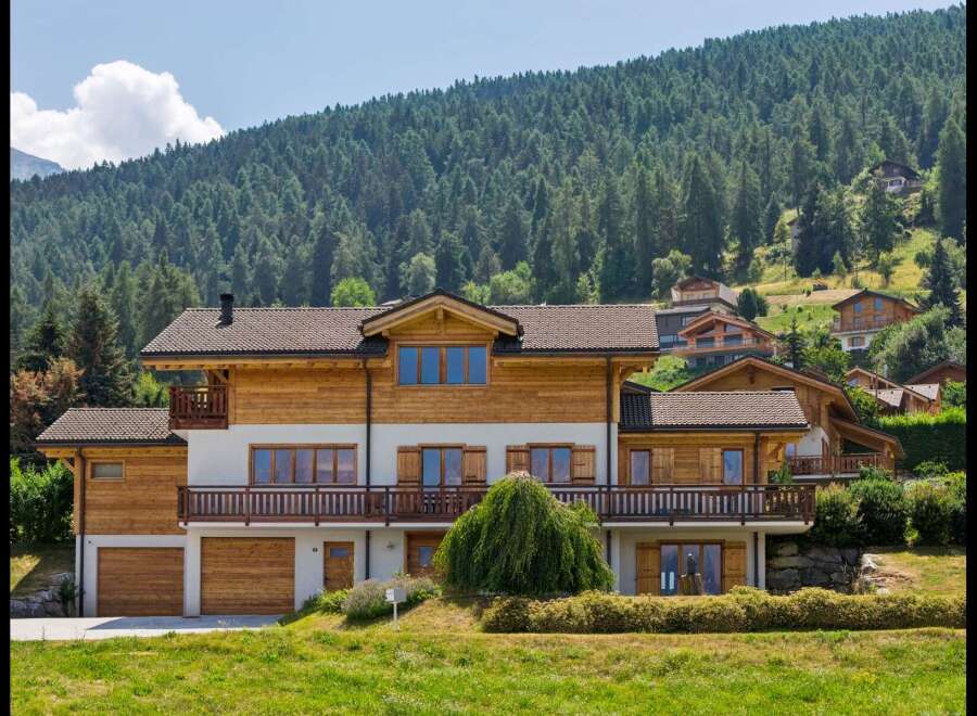 Experience luxury mountain living in this stunning chalet-style home, nestled against a backdrop of lush evergreen forests.