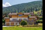 Experience luxury mountain living in this stunning chalet-style home, nestled against a backdrop of lush evergreen forests.