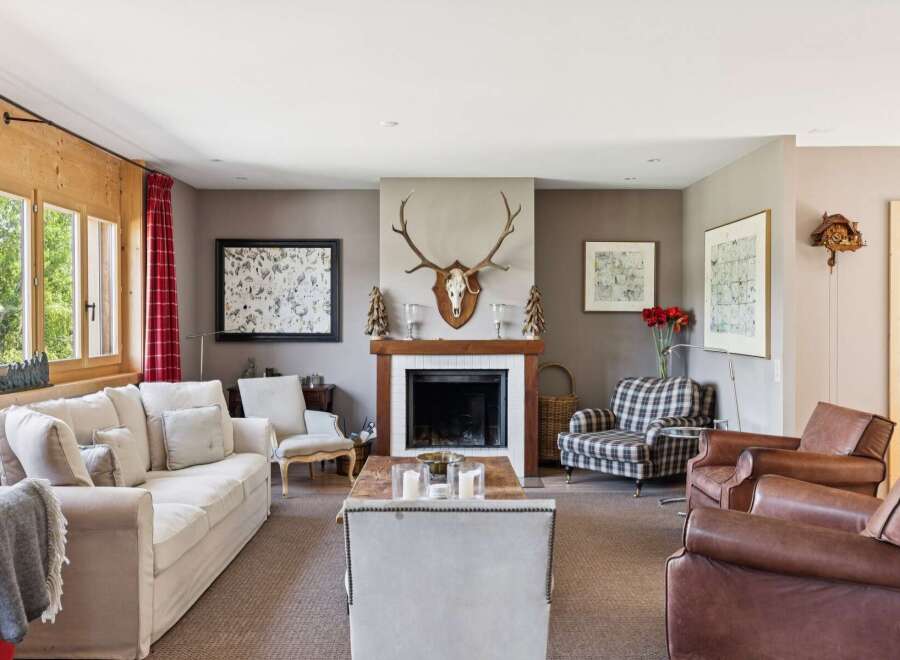 Experience rustic charm in this inviting living room, featuring a grand fireplace adorned with a mounted deer head and a cozy seating area.