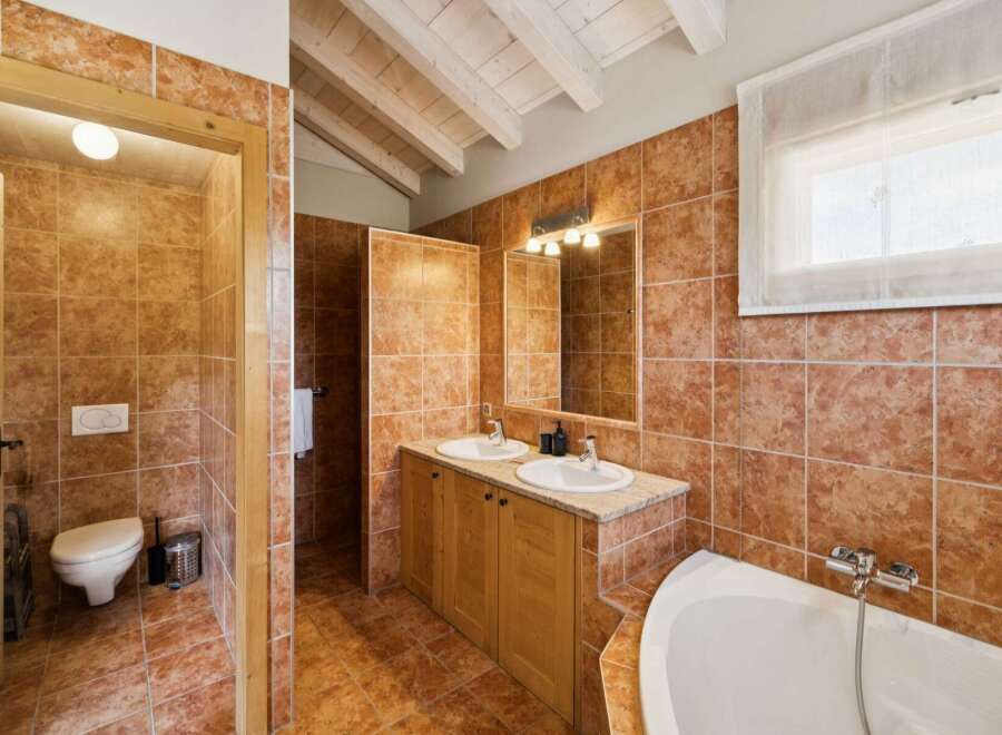 This charming bathroom features rustic terracotta tiles throughout, creating a warm and inviting atmosphere.