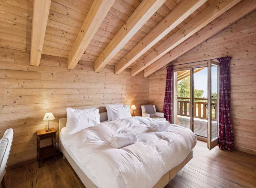 Experience rustic charm and modern comfort in this beautifully appointed bedroom, featuring a plush king-sized bed with crisp white linens and fluffy towels.