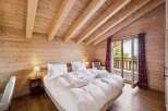 Experience rustic charm and modern comfort in this beautifully appointed bedroom, featuring a plush king-sized bed with crisp white linens and fluffy towels.