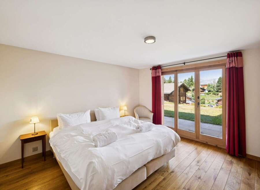 Experience ultimate comfort in this serene bedroom, featuring a plush king-sized bed adorned with crisp white linens and fluffy towels.